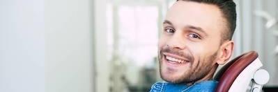 man smiling in dental chair after tooth extraction in wellington